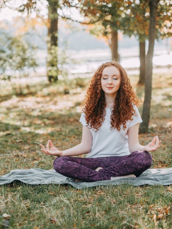 Person stretching gently outdoors in a park setting.
